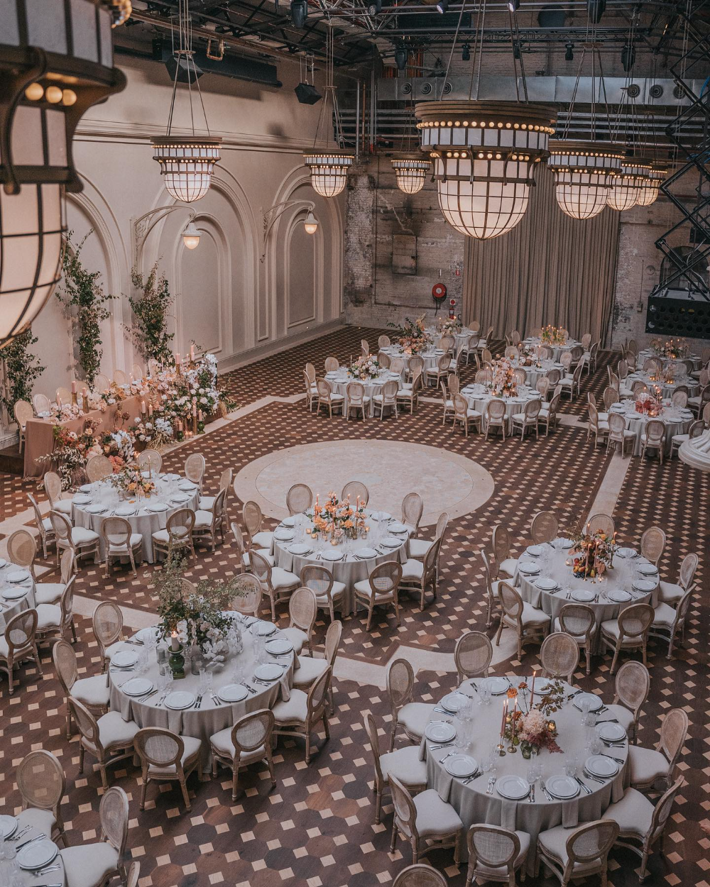 A wedding reception set to the approved floorplan: round tables, a long head table, and a central dance floor